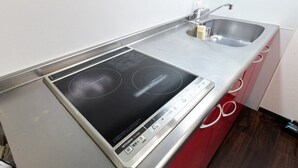 A kitchen with a built-in induction cooktop and a stainless steel sink. - XS16 XROSS STAY Namba8 (大阪市中央区島之内)