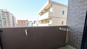 A balcony with a brown metal railing, a white door handle, and a tiled wall. - XS16 XROSS STAY Namba8 (大阪市中央区島之内)