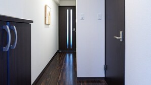 A hallway with dark wooden flooring, white walls, and a door with a silver handle. - XS16 XROSS STAY Namba8 (大阪市中央区島之内)