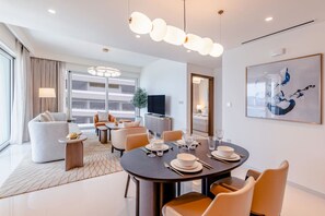 Une chambre d’hôtel moderne dotée d’un coin repas, d’un canapé, d’une télévision et d’une grande fenêtre.