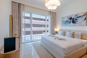 A hotel room with a large bed, a view of the building outside, and a painting on the wall.