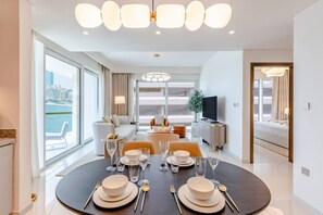 Una sala de estar moderna con comedor para cuatro personas, ventanas amplias y vistas a la ciudad.