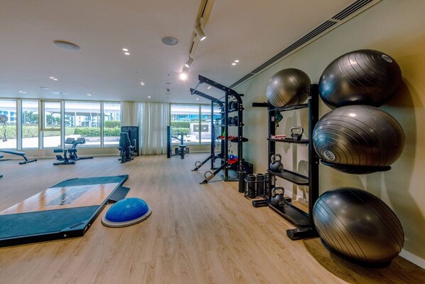 Un gimnasio con equipo de ejercicio, una pelota de ejercicios azul y una estructura para pesas.