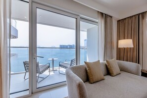 Une chambre d’hôtel avec un balcon, un canapé, une table et une lampe.