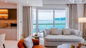A modern hotel room with a sofa, armchair, and dining area.
