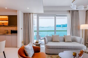 Una habitación de hotel moderna con sofá, sillón y zona de comedor.