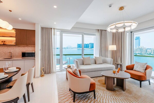 A modern hotel room with a dining area, a sofa, and a view of the city.