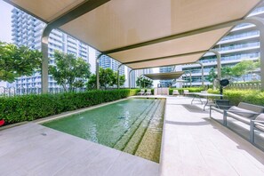 A rooftop pool area with a covered seating area and a view of high-rise buildings.