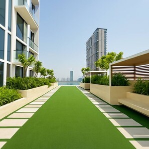 A modern building with a green pathway, white railings, and lush greenery. - Upscale 2Bedroom w/ Private Balcony Pool in JVC (Dubai)