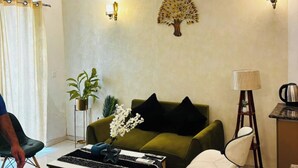 Un salon moderne avec un canapé vert, une table basse en bois, un lampadaire et un ventilateur de plafond.