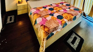 Une chambre à coucher avec un lit, une table de chevet, une lampe, un ventilateur de plafond et un tableau au mur.