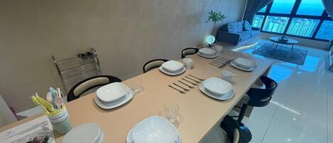 A dining area with a table set for six, a plant, and a view of the city through large windows.