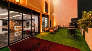 Vestíbulo de hotel con mostrador de recepción, zona de estar y plantas de interior.
