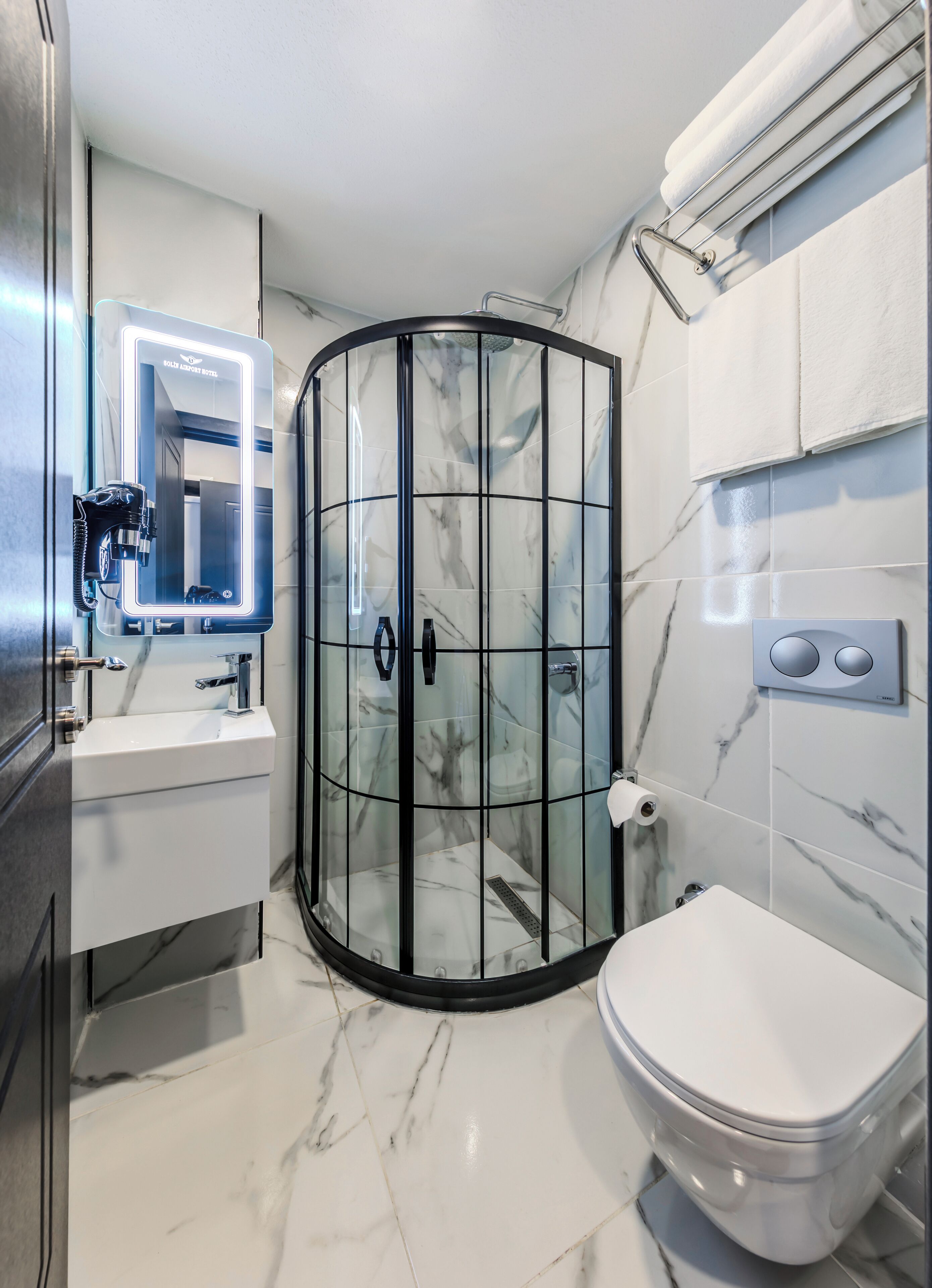 Un baño moderno con ducha de vidrio, lavamanos blanco y retrete.