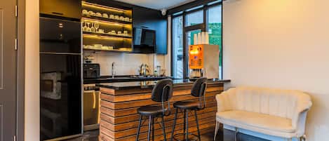 A modern kitchen with a built-in island, bar stools, and a white sofa.