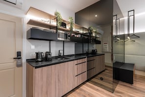A modern kitchen with a central island, built-in appliances, and a glass partition. - Guestready - Mercadores 150 (Porto)