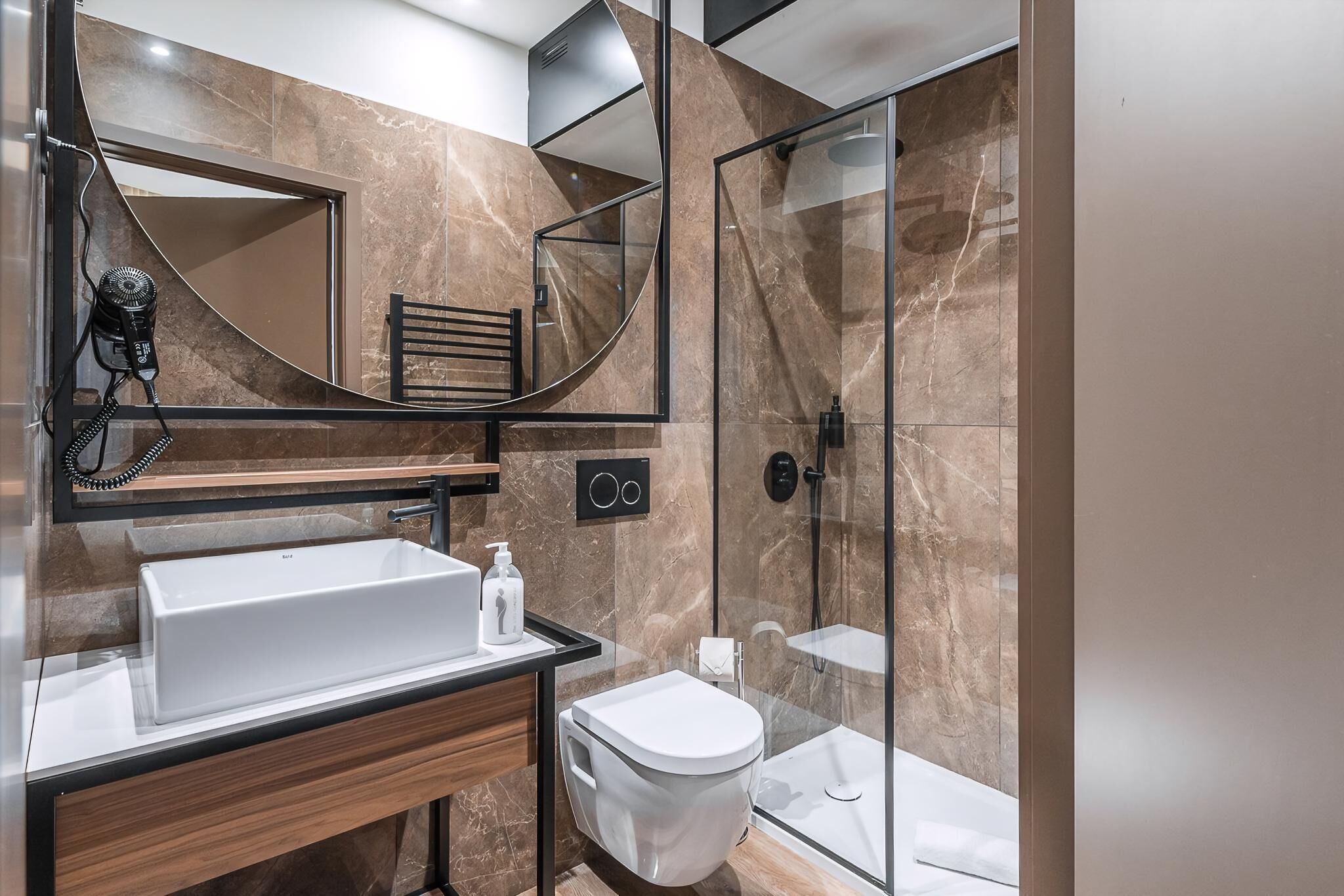 A modern bathroom with a large mirror, a sink, a toilet, and a glass-enclosed shower.