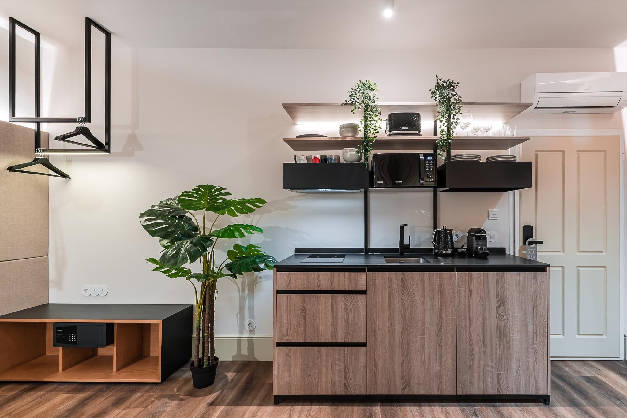 Une cuisine moderne avec un îlot central, des meubles en bois, un plan de travail noir et une plante en pot.