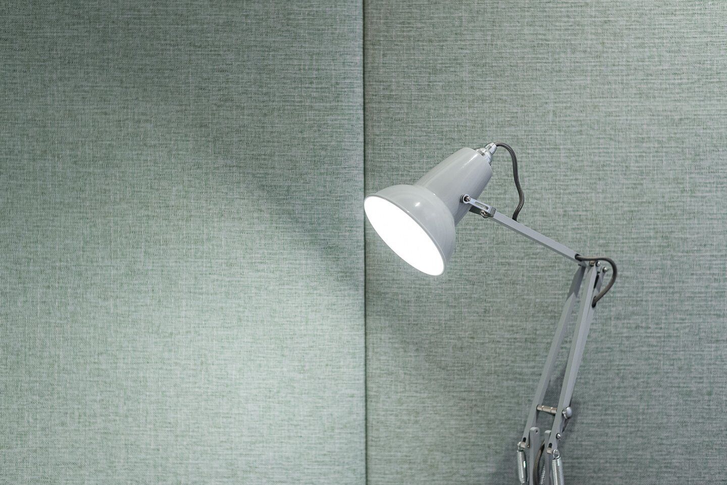 Una lampada da scrivania con braccio flessibile su una parete strutturata.
