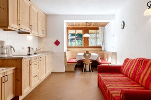 Une cuisine avec des meubles de rangement en bois, une table à manger avec un banc rouge et un canapé rouge.