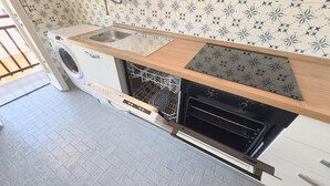 A compact kitchen with a built-in washing machine, a dishwasher, and a small oven. - Casa Puni in seaside (Chiavari)