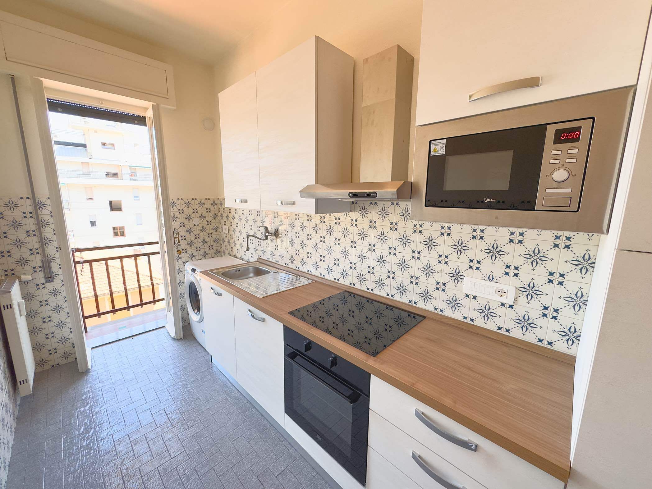 A compact kitchen with a washing machine, a microwave, and a sink.