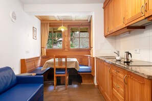 A compact kitchen with wooden cabinets, a built-in bench, and a window with curtains.