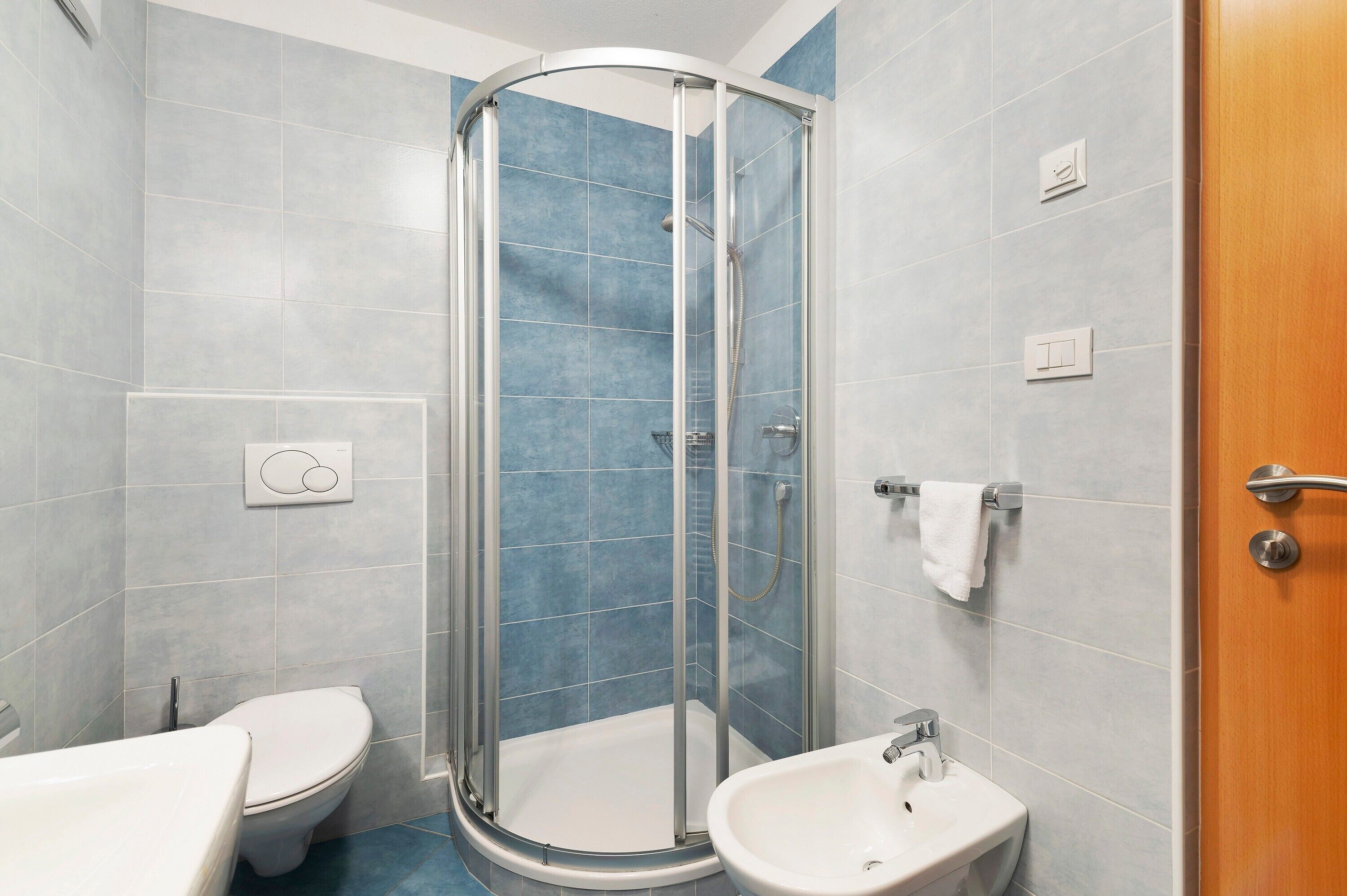 Un baño con ducha de vidrio, inodoro y lavamanos.