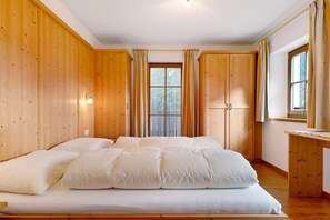 A wooden-paneled room with a bed, a window, and a wooden desk.