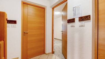 Un couloir avec des portes en bois portant les inscriptions « Zimmer » et « Dorfblick », et un panneau mural indiquant « Informations rapides ».