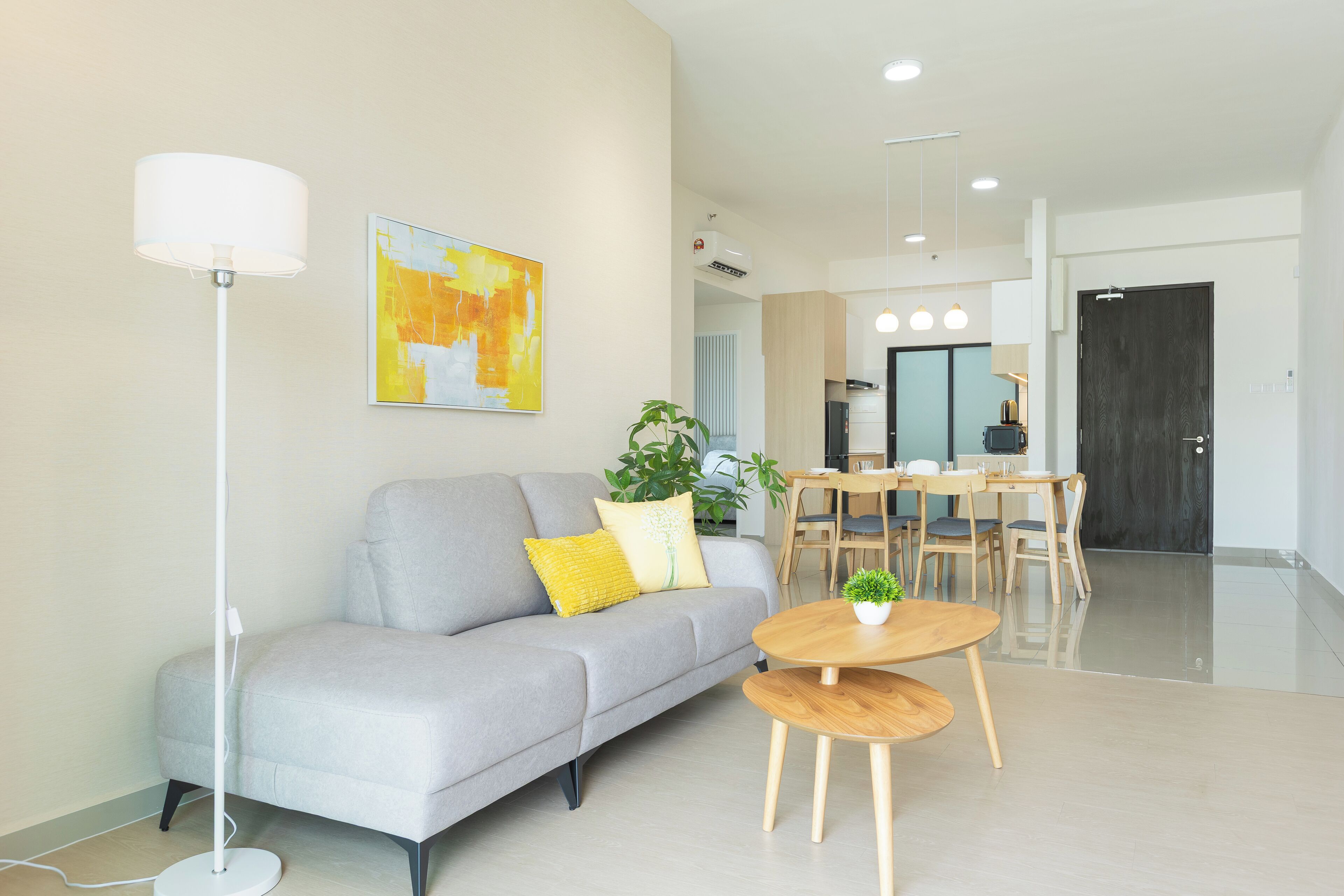 A modern living room with a grey sofa, a round wooden coffee table, and a floor lamp.