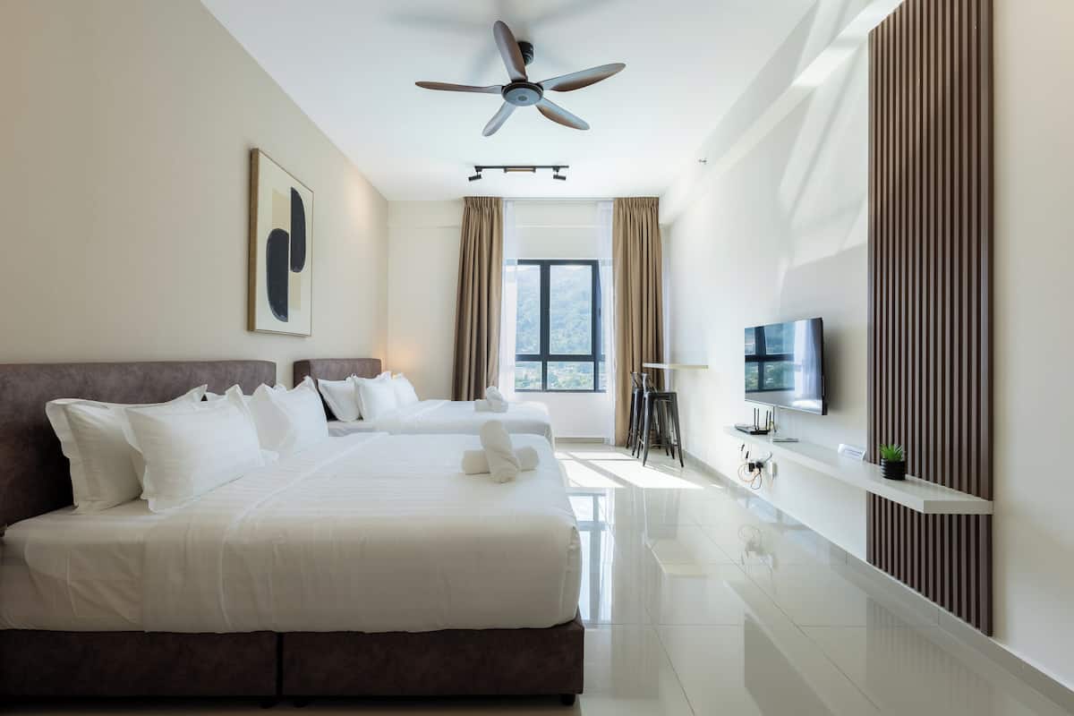 Una habitación de hotel moderna con una cama grande, ventilador de techo, televisión y ventana con cortinas.