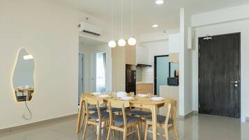 A modern dining area with a round table, six chairs, and pendant lighting.