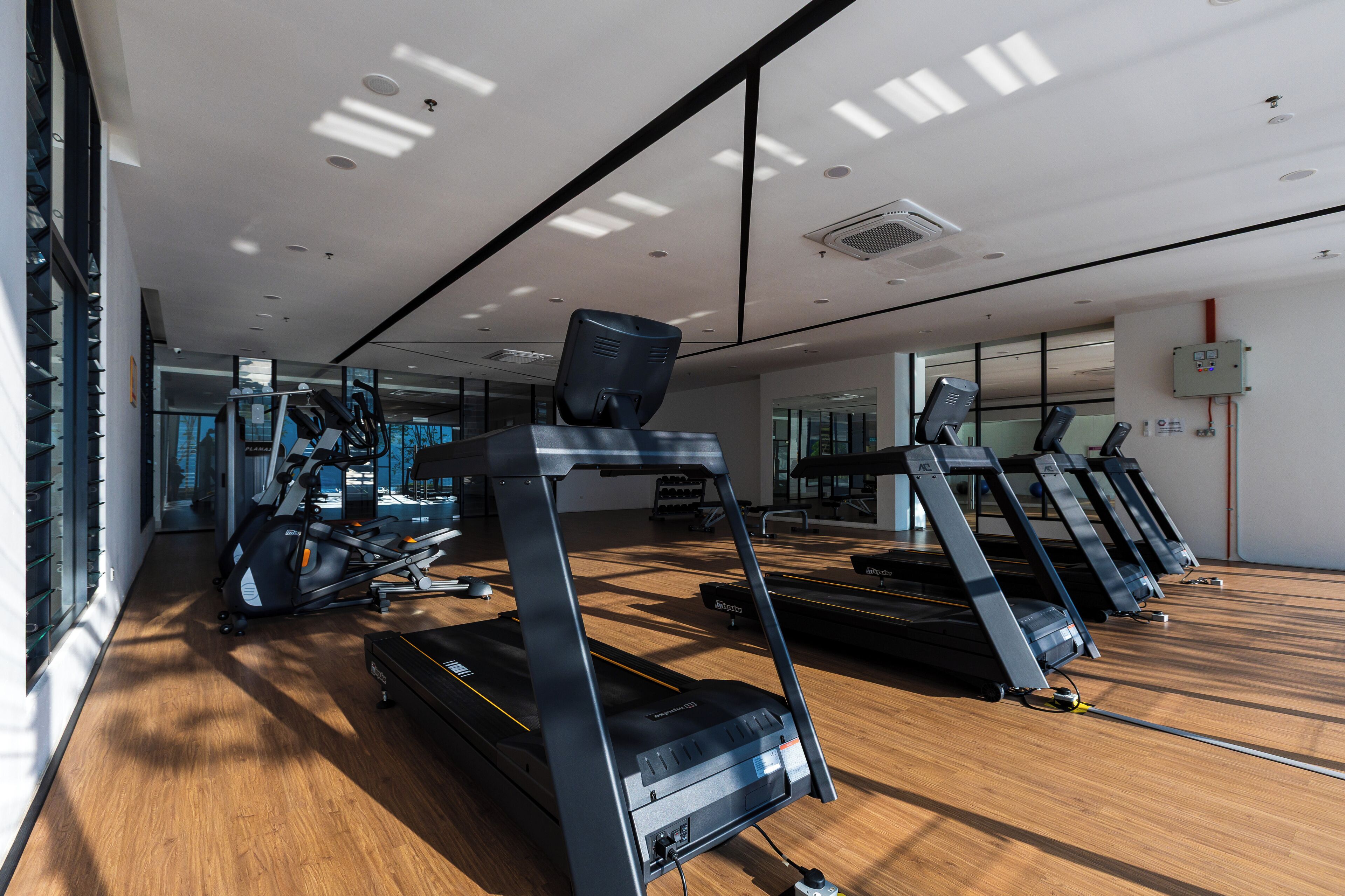 A gym with treadmills, exercise bikes, and a mirrored wall.