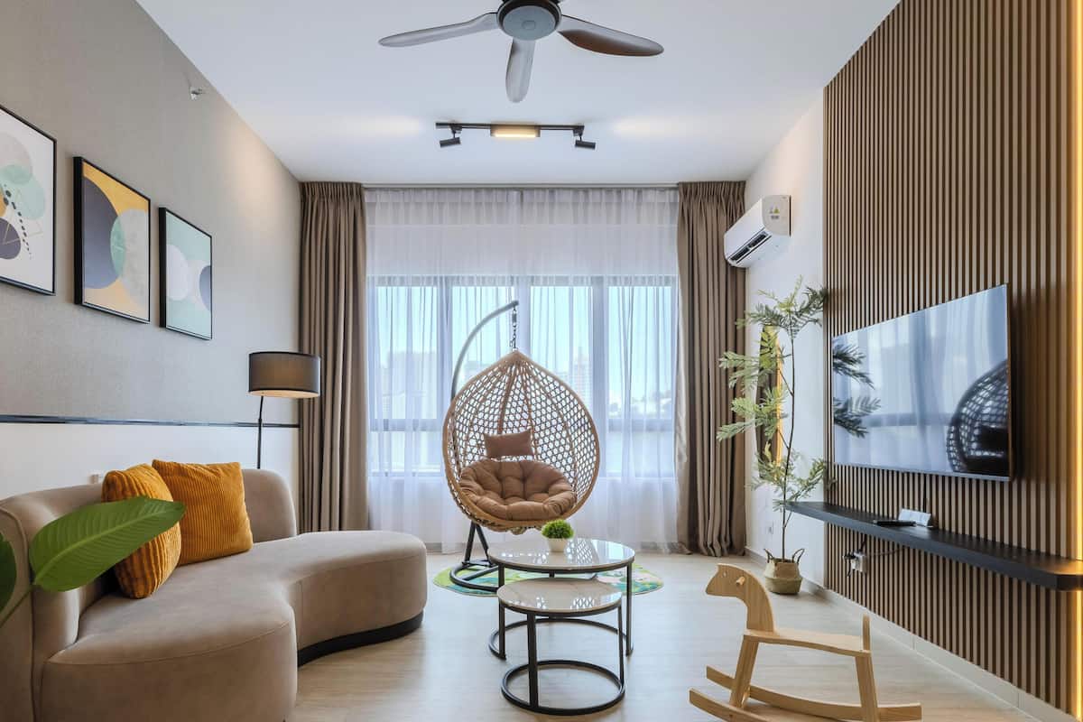 Una sala moderna con un sofá, una silla colgante, un televisor y un ventilador de techo.