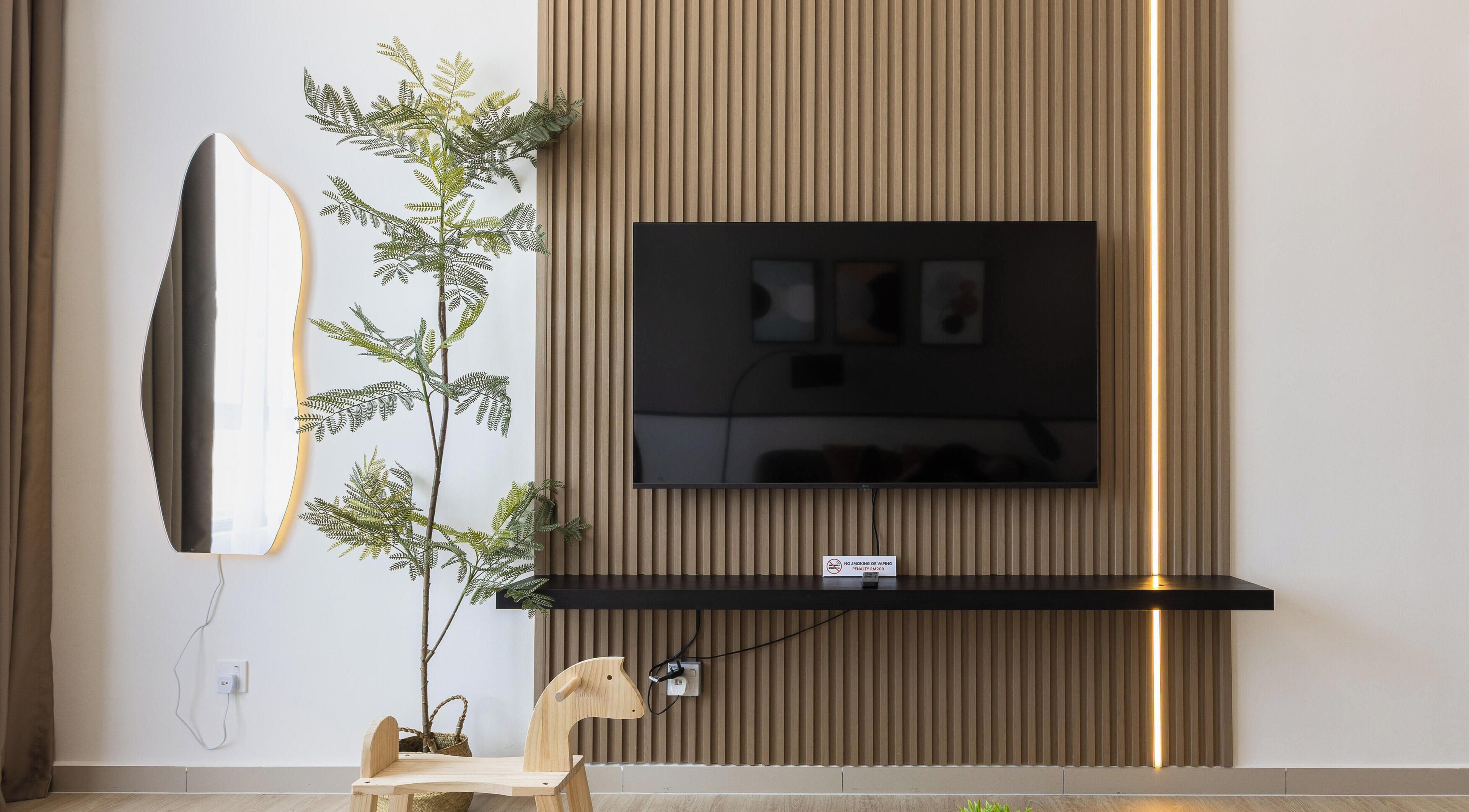 Un salon moderne avec un téléviseur fixé au mur, une décoration sur le thème du surf, une chaise en bois et une plante en pot.
