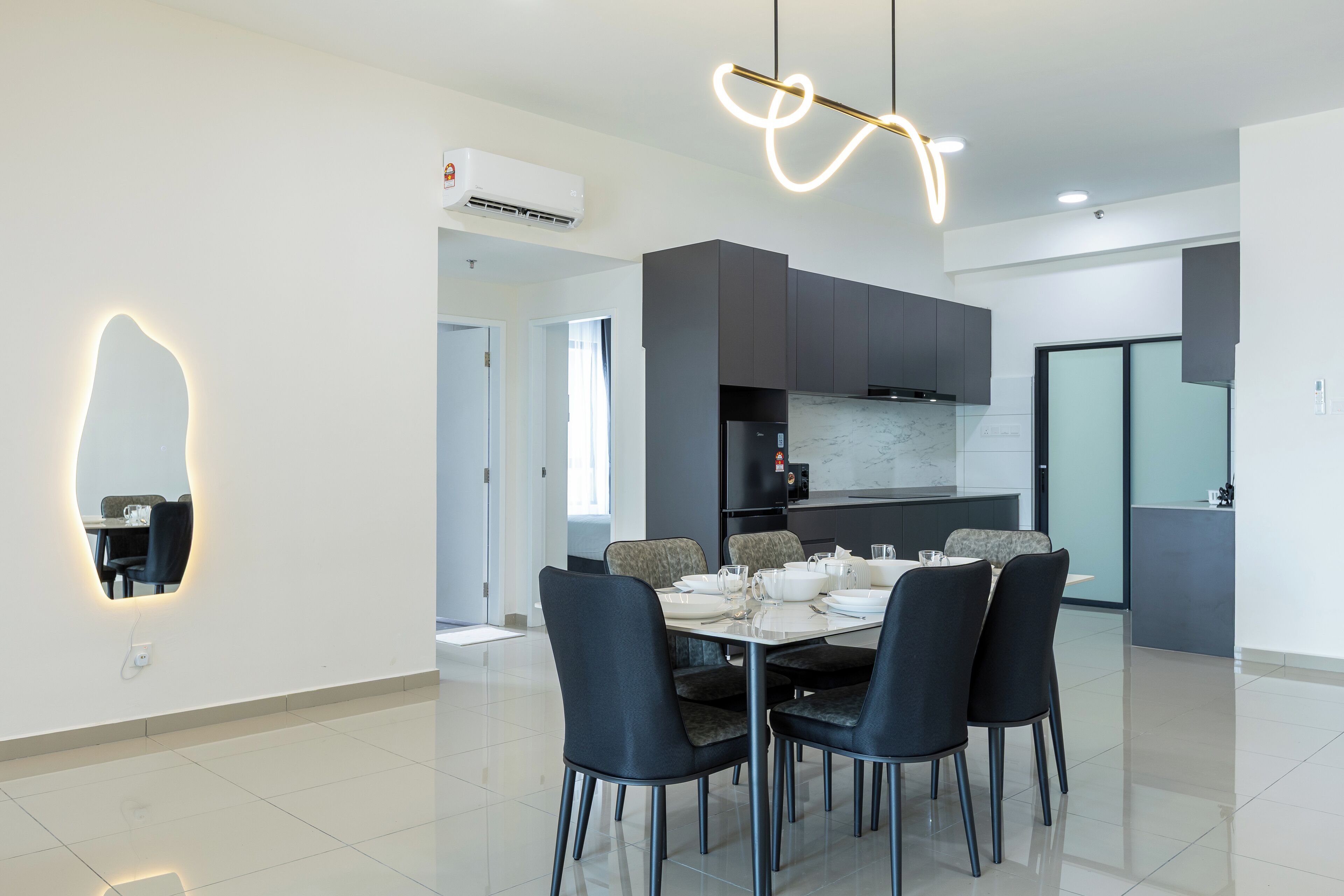 A modern dining area with a rectangular table, black chairs, and a unique wall-mounted light fixture.