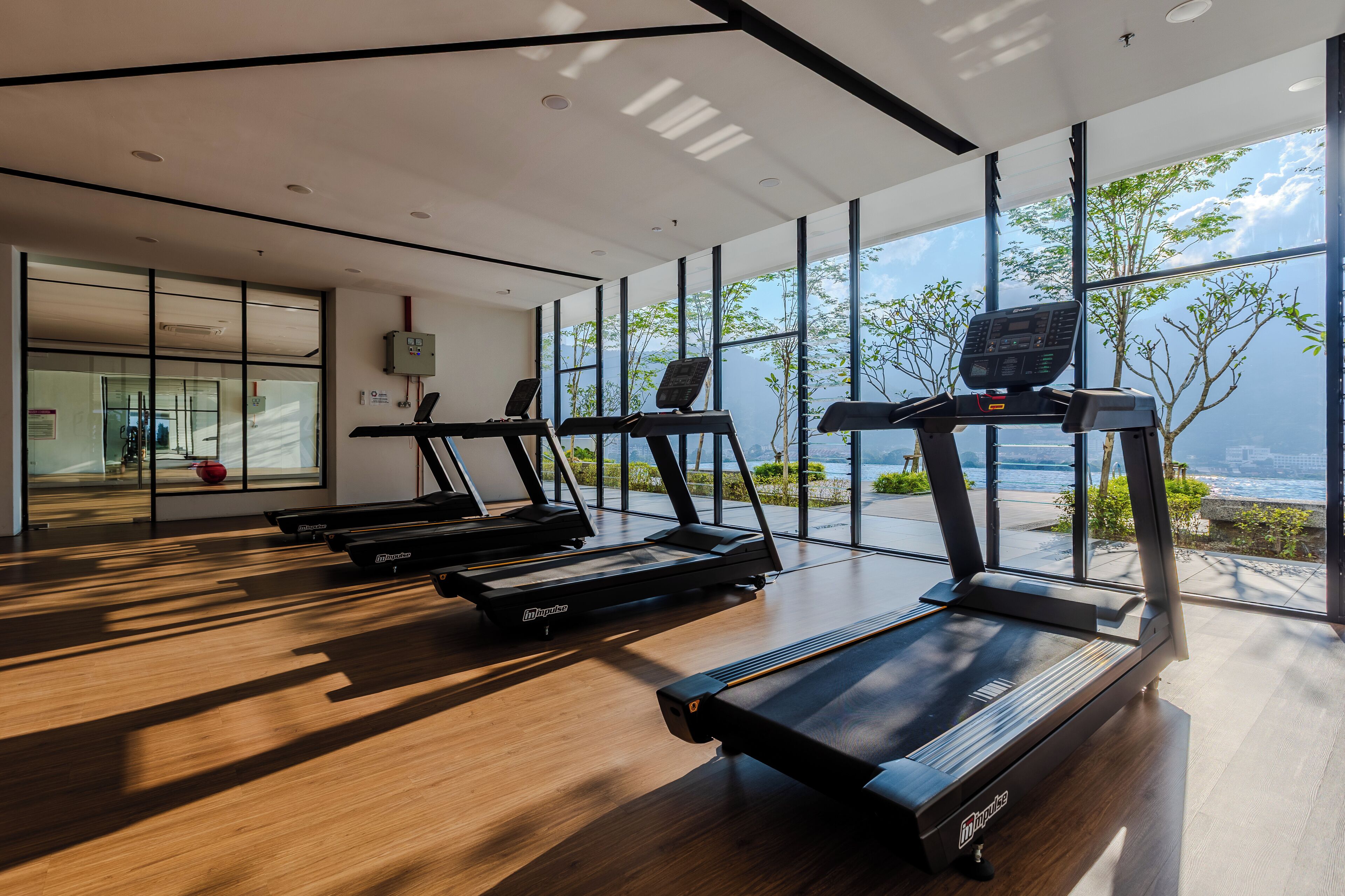 Une salle de sport équipée de tapis de course et offrant une vue sur la mer.