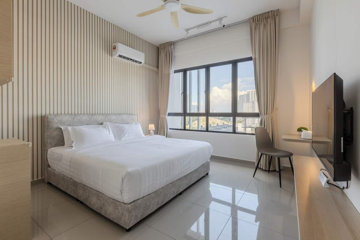 Una habitación de hotel moderna con una cama grande, un escritorio con silla, un televisor y una ventana con vista a la ciudad.