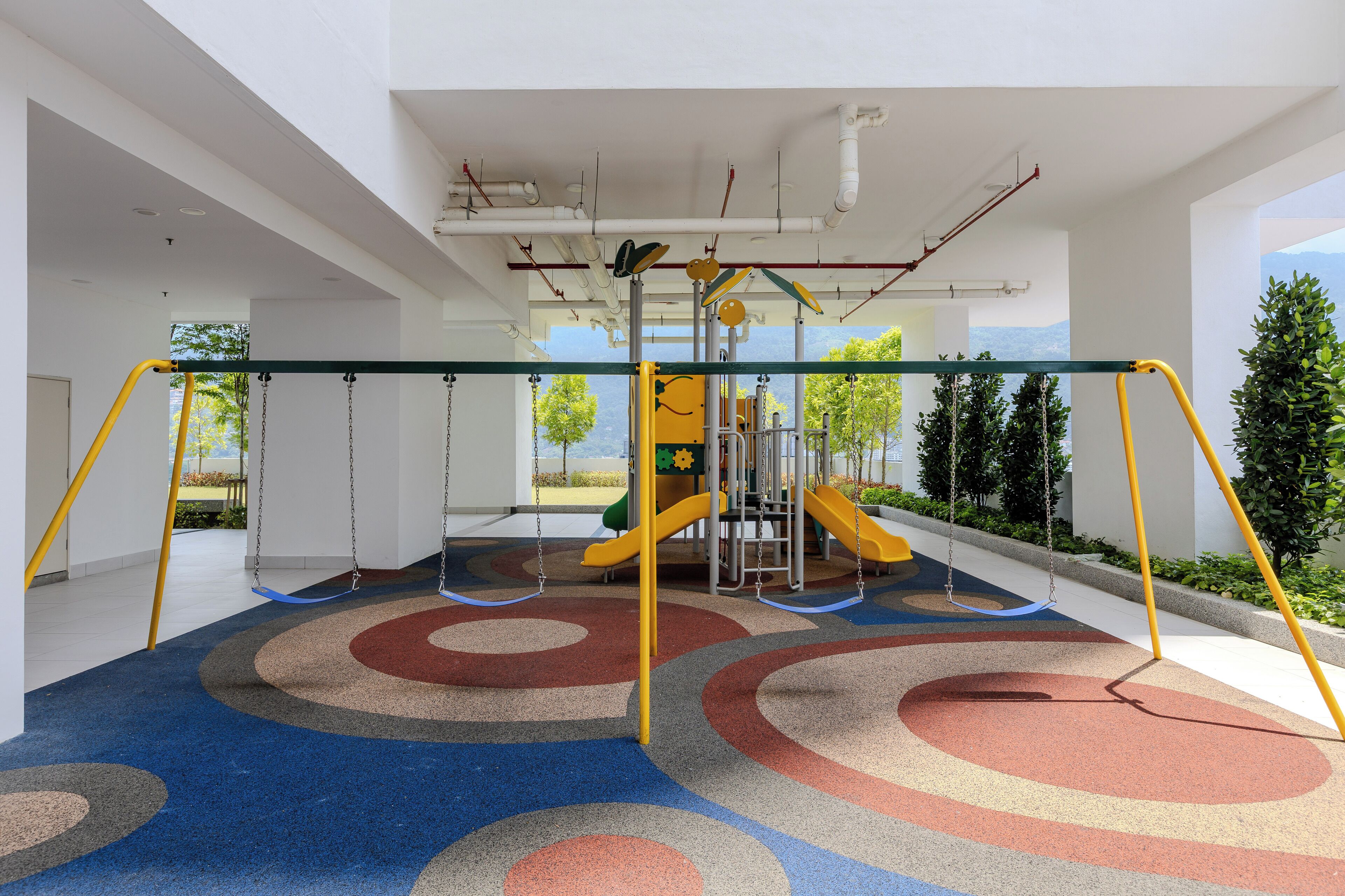 A modern indoor playground with swings, slides, and a climbing structure.