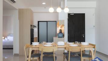 A modern dining area with a wooden table set for four, a television, and a kitchen in the background.