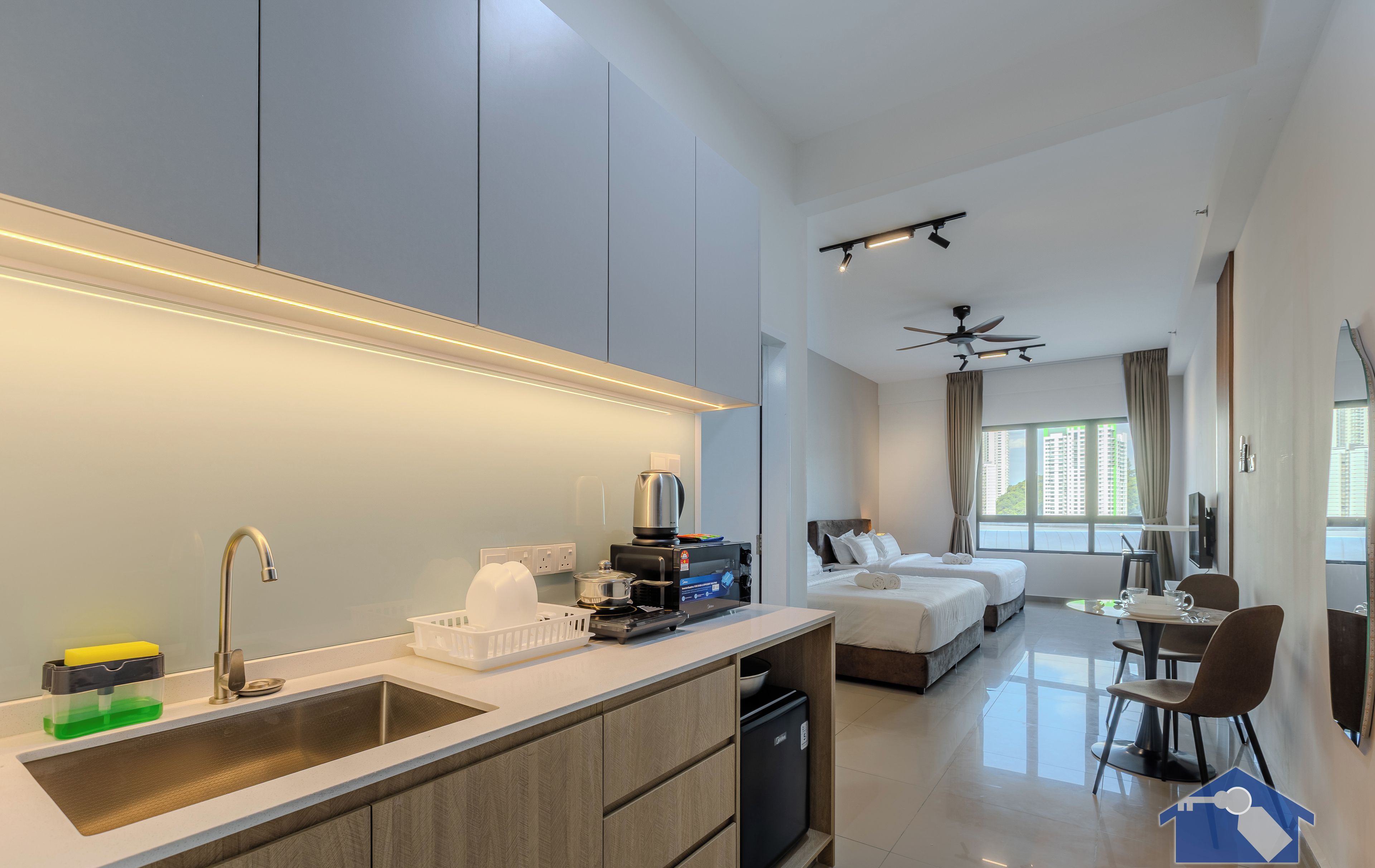 Una habitación de hotel moderna con cocina, una mesa de comedor y un dormitorio con dos camas.