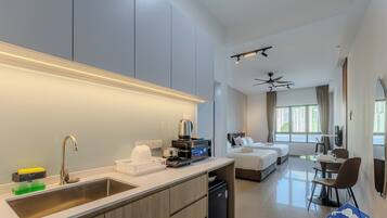 Una habitación de hotel moderna con cocina, una mesa de comedor y un dormitorio con dos camas.