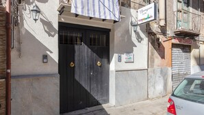 A building with a black gate, a sign for 'Margarino Suites,' and a car parked nearby. - Mangano Suite Apartment (Palermo)