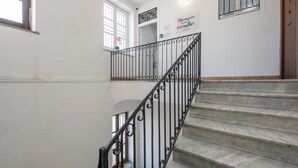 A staircase with a metal railing, a potted plant, and a sign on the wall. - Mangano Suite Apartment (Palermo)