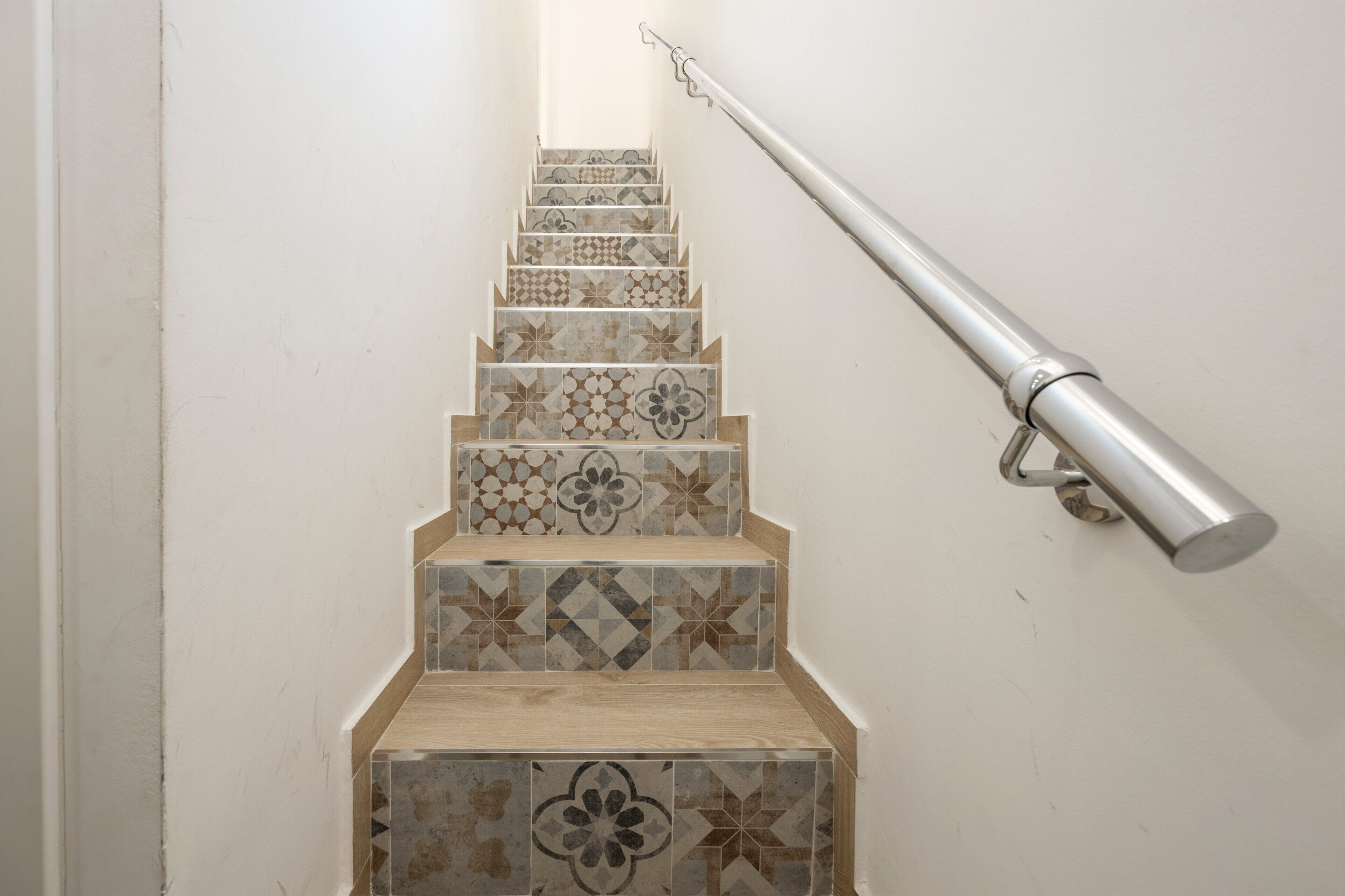 Eine Treppe mit gemusterten Fliesen und einem Metallgeländer.