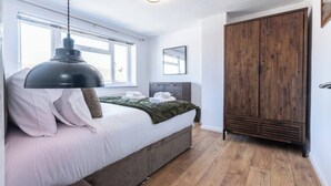 A bedroom with a bed, a wardrobe, a mirror, and a hanging light fixture.