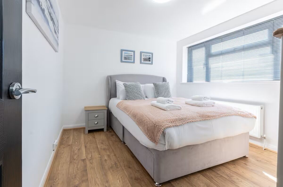 Un dormitorio moderno con una cama grande, mesitas de noche y una ventana con persianas.
