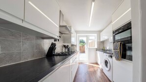 A modern kitchen with a long countertop, built-in oven, and a washing machine.