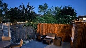 An outdoor patio with wicker furniture, a wooden deck, and string lights.